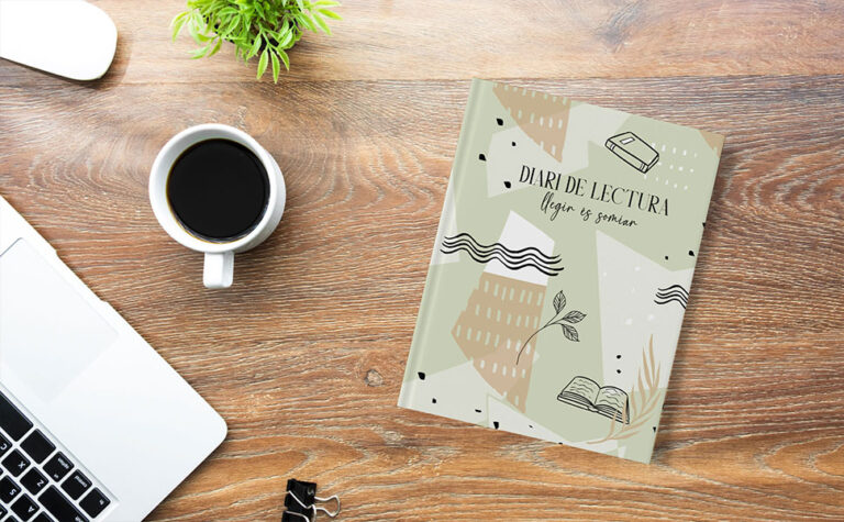 Diari lector de Caliu Journals amb bolígraf i llibre al costat en ambient acollidor